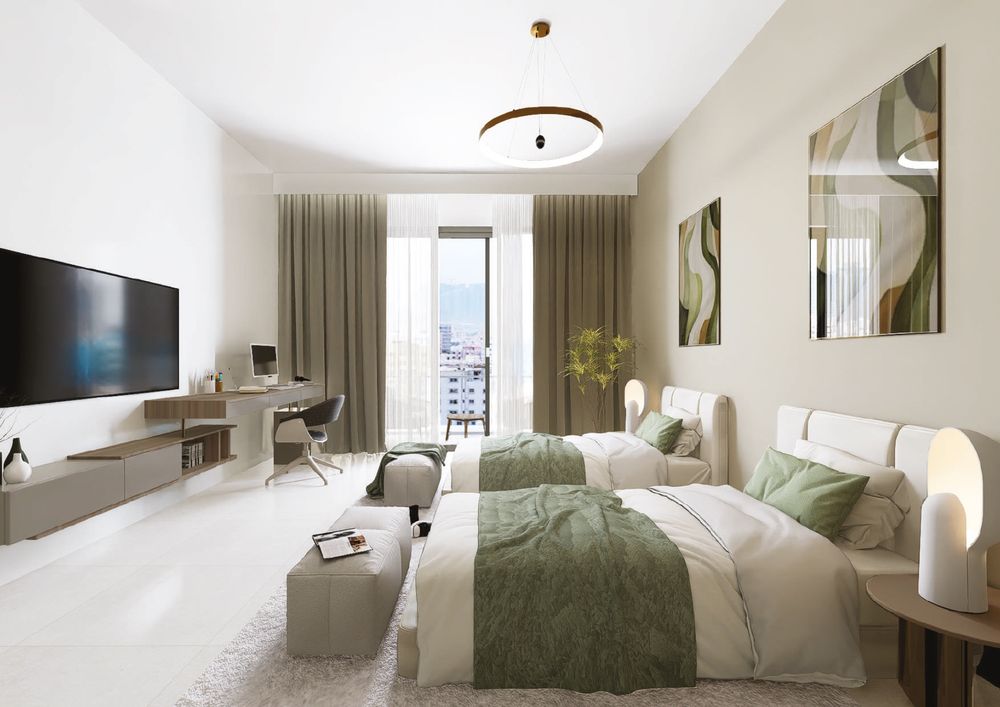 Furnished bedroom with TV wall and work desk, Al Ameera Village brochure image